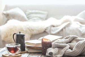 Still life home comfort in the living room with a Cup of tea and a kettle , near a burning candle and a knitted sweater.The concept of home atmosphere and comfort